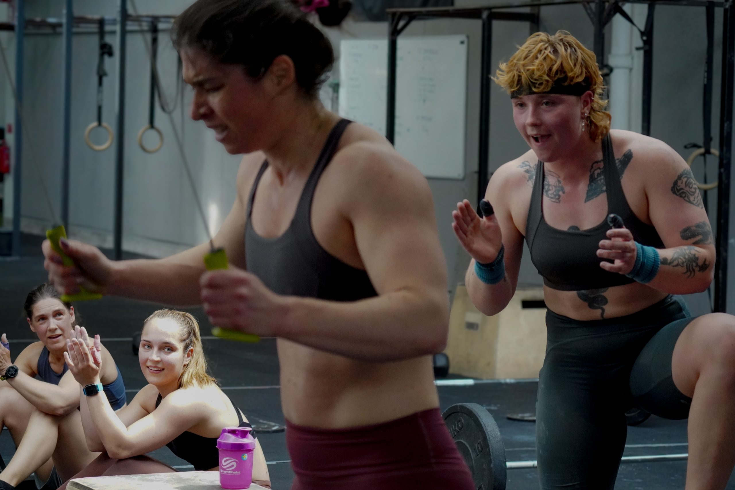 Tjej som blir påhejad av kompisar vid skiergen på gymmet.